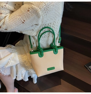 Detail of woven bucket bag with green leather handles and detachable shoulder strap
