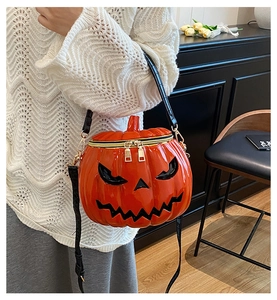 Detail of pumpkin-shaped crossbody bag featuring black crocodile texture strap and golden zipper