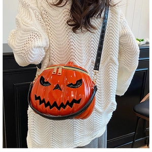 Detail of a 3D pumpkin cross-body bag featuring a glossy orange finish and black straps