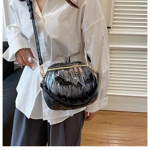Detail of black metallic pumpkin crossbody bag with crocodile texture strap and gold zippers