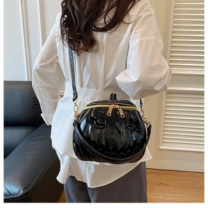 Detailed close-up of glossy black pumpkin bag with premium golden metal zippers