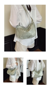 Detail view of light green pleated half-moon bag with decorative plush bear charm