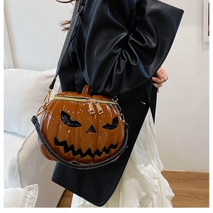 Close-up of gloss orange pumpkin crossbody bag featuring dual gold zippers and smiley face