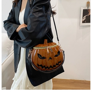 Detail of a shiny pumpkin shaped crossbody bag with black face carving for Halloween