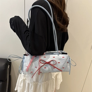 Light blue canvas shoulder bag with red bow pattern and lace trim worn by a model