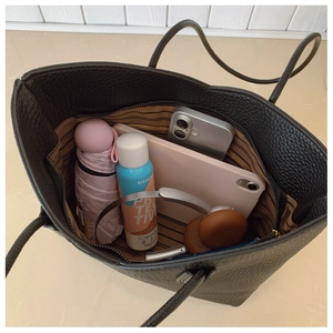 Spacious black pebbled leather tote interior with striped lining and daily essentials