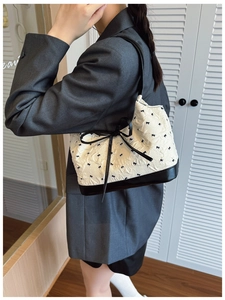 Chic white bubble textured underarm bag with black bow details worn by a model