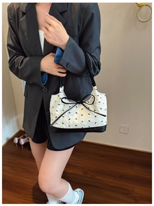 Close-up of white jacquard fabric texture and black leather handle on underarm bag