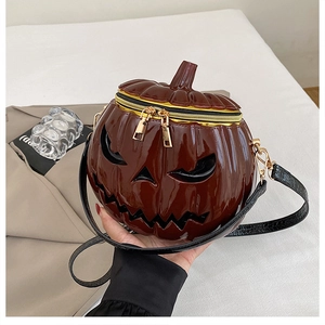 Detail of a deep brown pumpkin crossbody bag featuring dual zippers and 3D face design