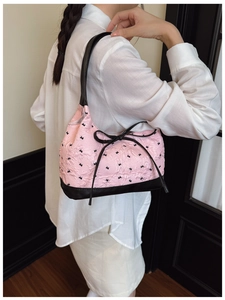 Detail of pink jacquard bow bag with black piping and bow accent on model shoulder