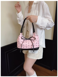 Close-up of pink textured fabric tote featuring black bow embroidery and leather trim