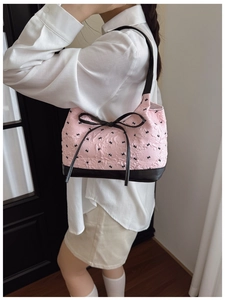 Macro detail of the 3D pleated texture and black butterfly prints on the pink shoulder bag