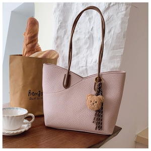 Detail of pink lychee leather tote bag with brown straps and cute bear charm ornament
