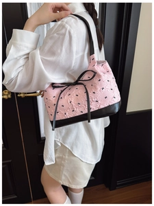 Detail of pink ruffled underarm bag with black bow patterns and leather shoulder strap