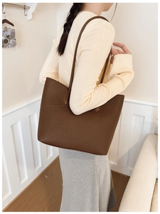 Detail of dark brown pebble leather tote bag with slim straps worn over the shoulder