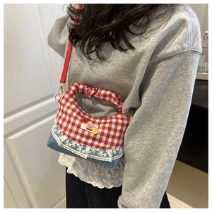 Close-up of red gingham and denim crossbody bag with lace trim and cherry patch