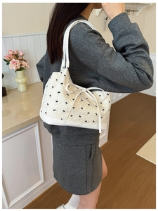 Detail showing the white quilted shoulder bag with small black bow embroidery and a large bow