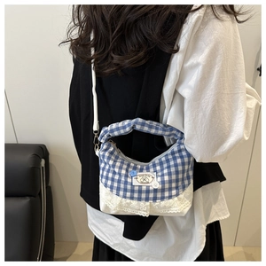Detail showing blue gingham pattern with white lace trim and decorative buttons on a bucket bag