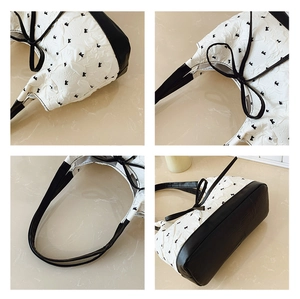 Detail view of white pleated fabric with black bow embroidery and leather strap textures