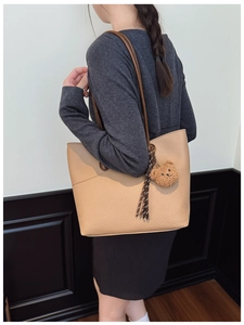 Detail of beige faux leather tote with brown straps and cute plush bear charm accessory