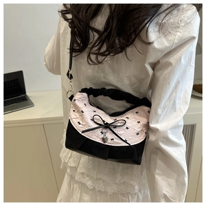 Detailed shot of pink and black crossbody bag with bow, heart pendant and cloud handle