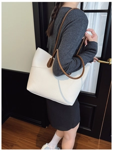 Close-up of white lychee pattern leather tote bag with brown straps on model