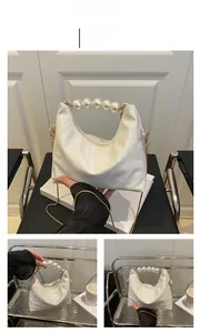 Detailed close-up of white crossbody bag with crocodile texture and pearl handle