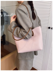 Close-up of pink lychee pattern leather tote bag with brown straps worn by a model
