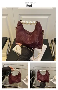 Detail of wine red embossed snakeskin bag with large faux pearl handle and gold chain