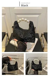 Detail of black faux crocodile leather bag with pearl handle and golden chain strap