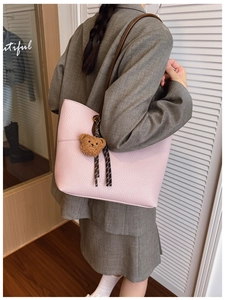 Pink lychee grain leather tote bag with plush bear charm and striped ribbon detail