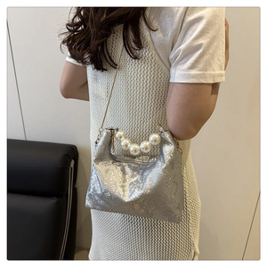 Detail of silver snake-pattern bag with large pearl handle and gold chain strap
