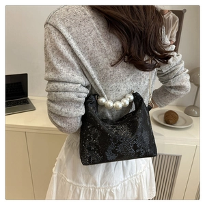 Detail of black snake pattern cloud bag featuring a large pearl beaded handle and gold hardware