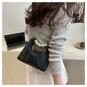 Detail of black snake print handbag featuring large pearls on the handle and PU leather texture