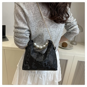 Close-up of black and white snakeskin pattern bag with pearl handle and gold chain