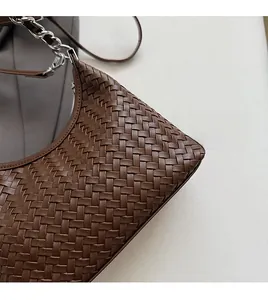 Detailed view of the dark brown woven leather texture and silver chain strap for this bag
