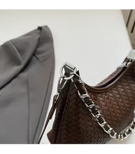 Close-up of woven leather texture and silver chain strap on dark brown shoulder bag