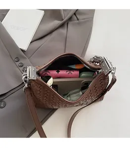 Detail view of woven brown shoulder bag showing large interior capacity with a zipper closure