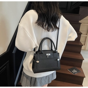 Minimalist black pebbled leather handbag with metal lock shown in model's daily wear shot
