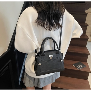 Crossbody black pebble leather handbag styled with white hoodie and pleated skirt