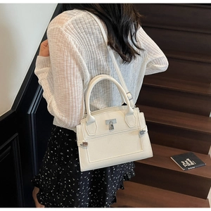 Close-up of white lychee leather handbag with metal lock buckle and handle detail