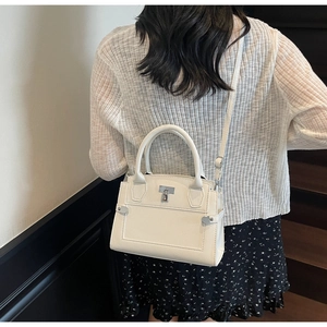 Detail of off-white lychee grain handbag with silver metal buckle on a model