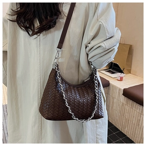 Close-up of dark brown woven leather texture and silver chain on the hobo handbag