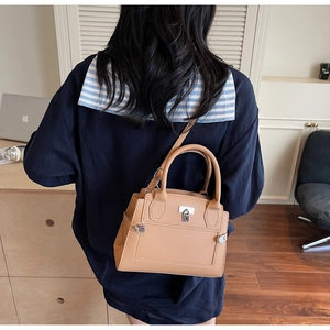 Detail of light brown lychee grain leather handbag with silver lock and shoulder strap