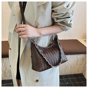 Detail of dark brown woven leather texture with silver chain and crossbody strap