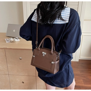 Detailed view of dark brown pebbled leather texture and silver clasp on the handbag