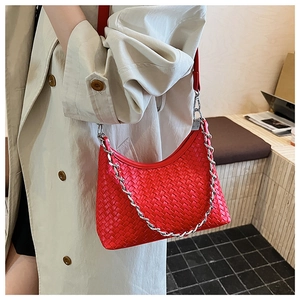 Detail of red woven leather handbag with silver chain strap on trench coat