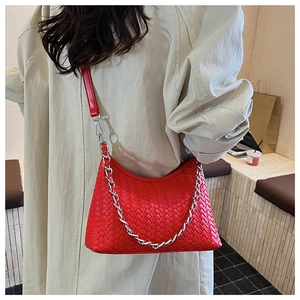 Model wearing a red woven leather crossbody bag with silver chain strap and top handle