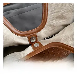 Detail of silver magnetic buckle, brown leather piping and woven texture on tote bag