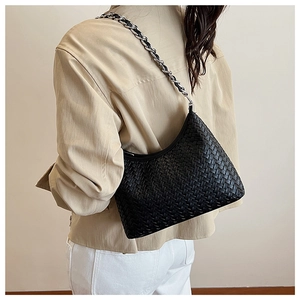 Detail of black woven leather shoulder bag with silver chain strap on a model